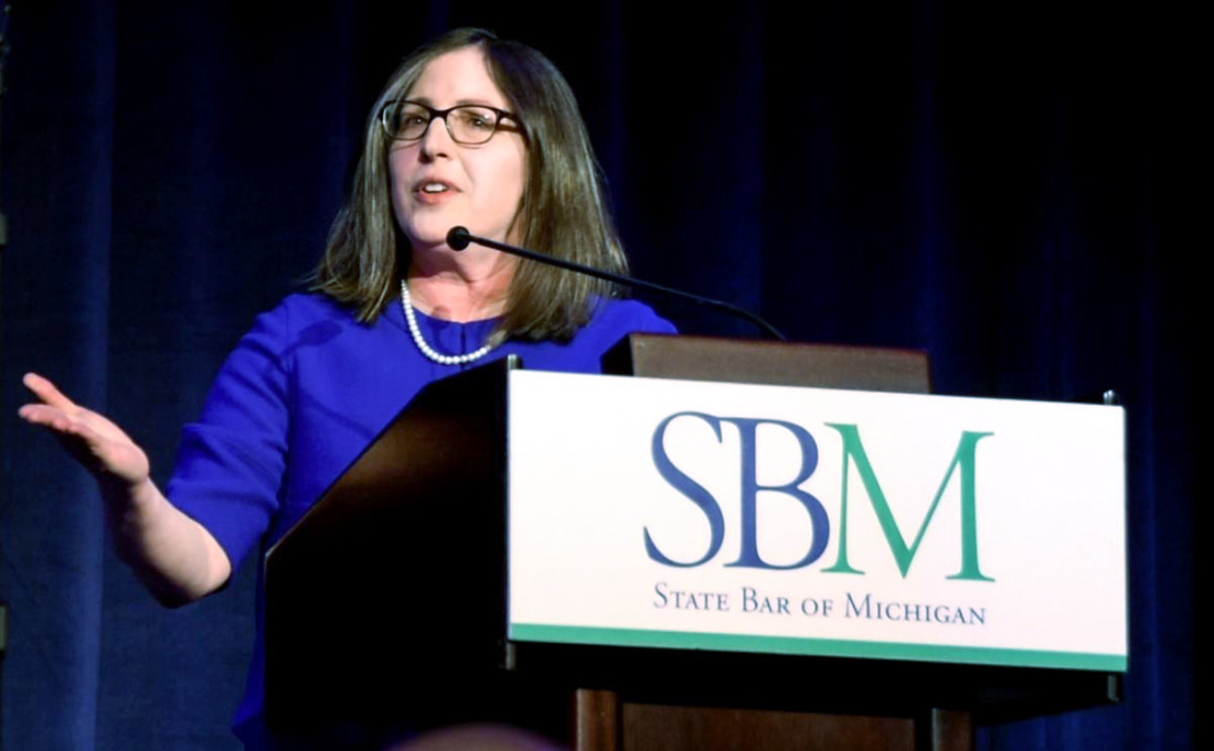 Julie Fershtman speaking Julie Fershtman in blue dress speaking at a podium