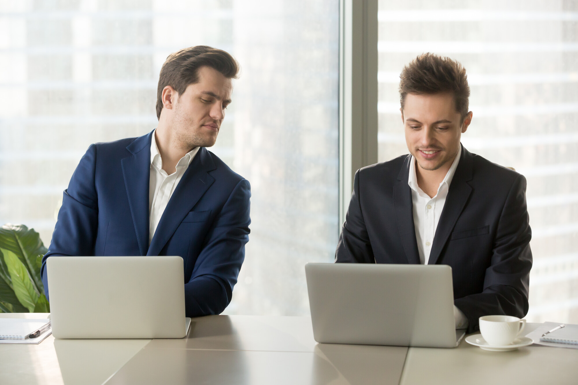 A man peeking over at the laptop next to him.