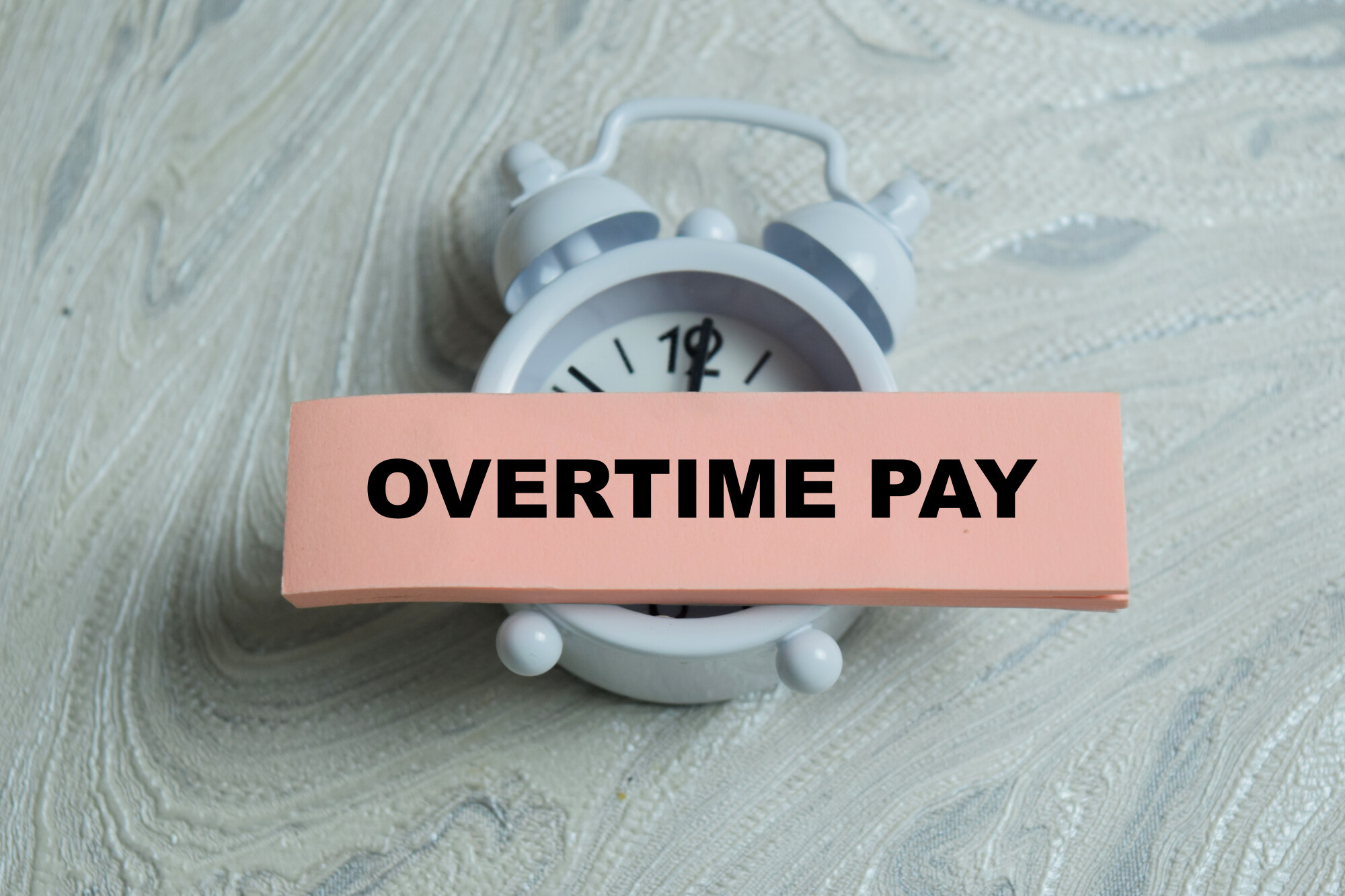 Concept of overtime pay write on sticky notes isolated on Wooden Table. For labor law and payroll 