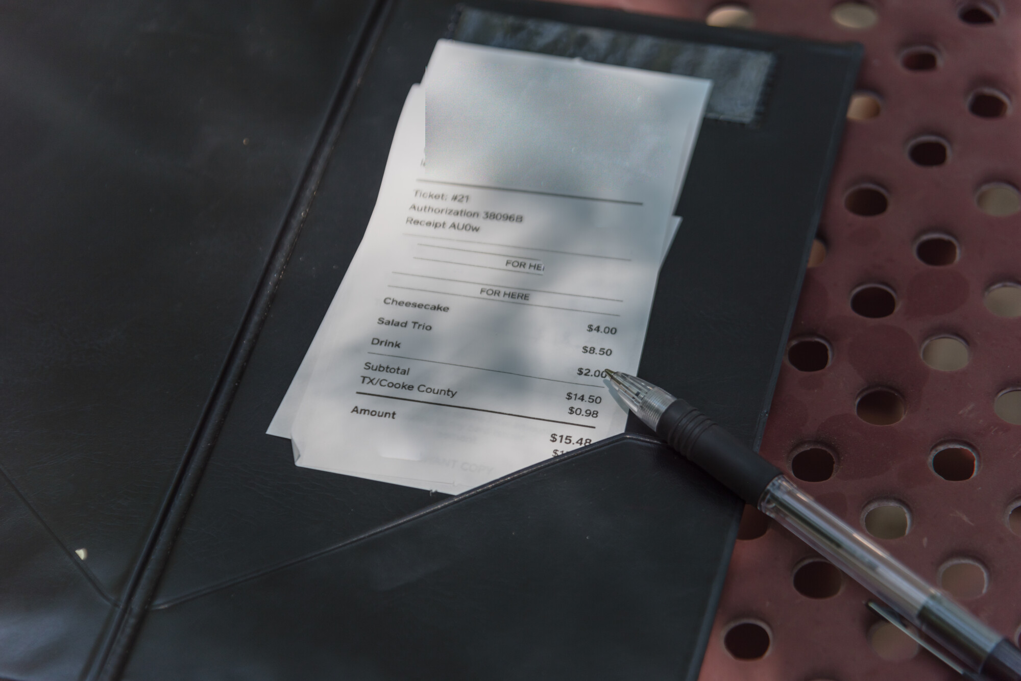 Close-up open leather bill holder with restaurant check and pen