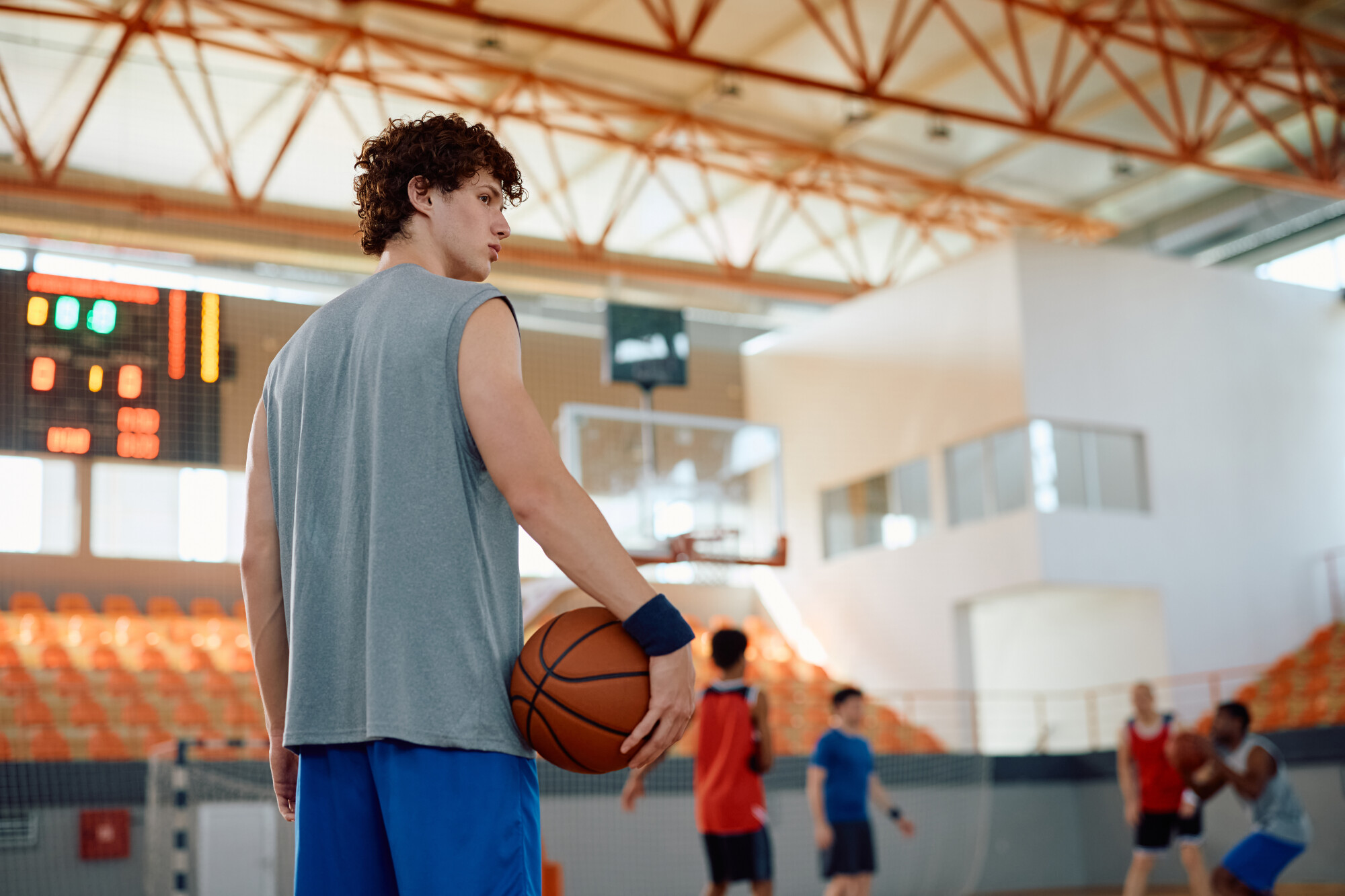 Young basketball player on court with his teammates playing in background. 