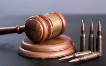 Wooden gavel and pounding block on blue background with bullet casings standing up