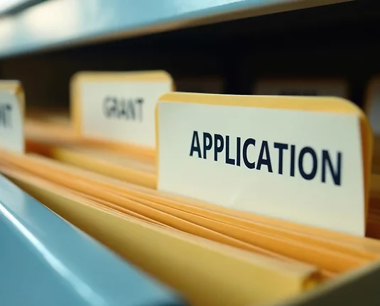 Metal file cabinet drawer open with manila envelopes with a label that says applications