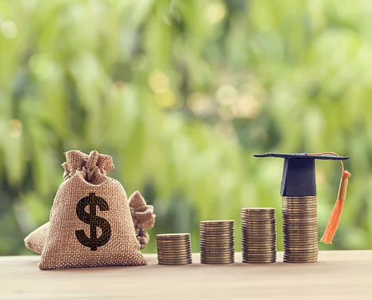 Stacks of coins increasing in height with the last having a mini graduation cap next to burlap money bag.