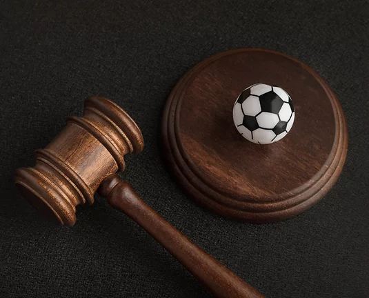 Gavel laying on Black Background and Mini Soccer Ball on Block
