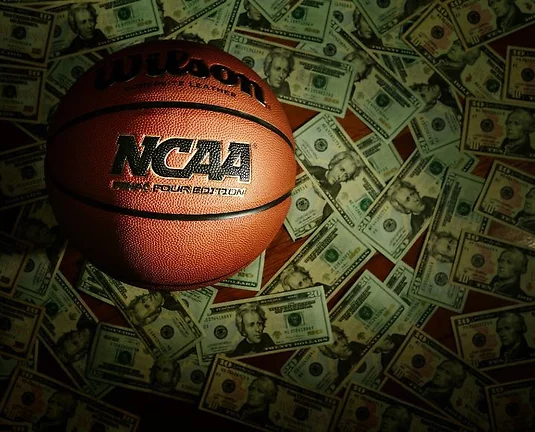Picture of NCAA basketball on a pile of US dollars.