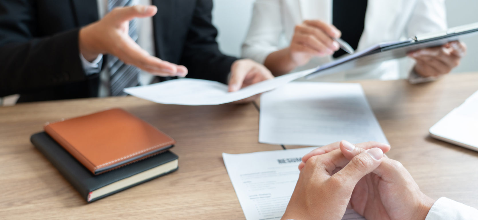 Hands holding resumes while interviewing man