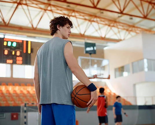 Young basketball player on court with his teammates playing in background.