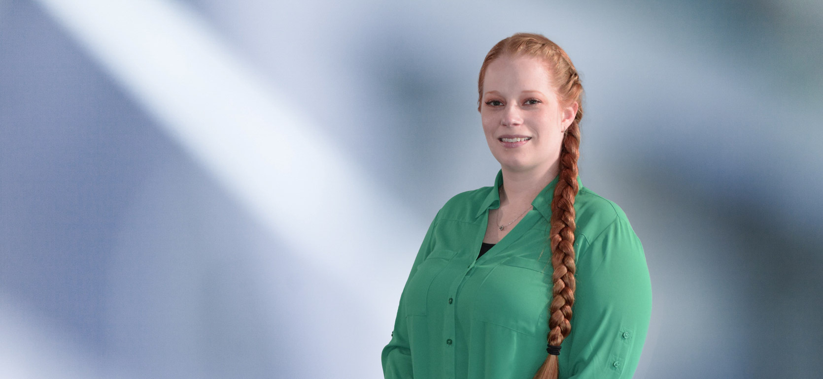 woman, Toni Harris, with shoulder-length blonde hair in a dark blazer, with a blurred blue and white background.