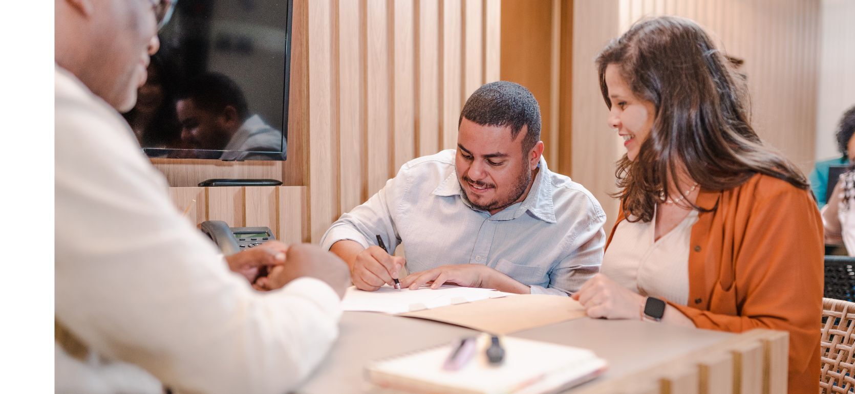 Two people smiling and signing documents.