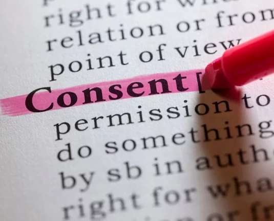 Close-up of the word "Consent" highlighted in pink in a printed text, with a pink highlighter pen marking the word.