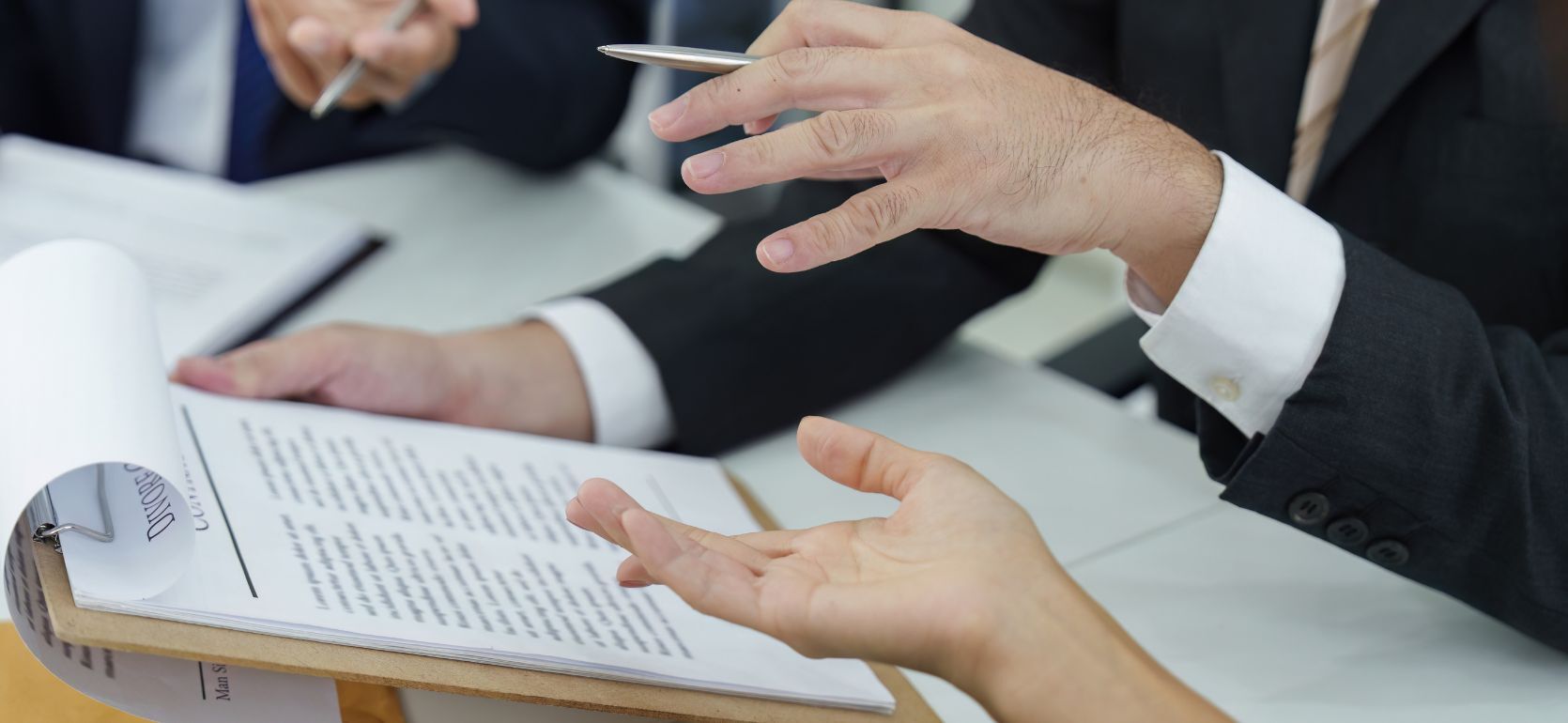 Three people discussing over a clipboard with papers.