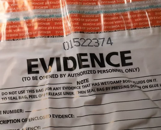 Close-up of a clear plastic evidence bag labeled "EVIDENCE" with a unique number and usage instructions
