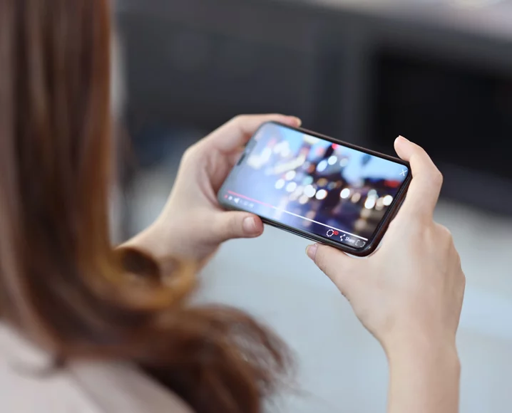 Hands holding cellphone sideways watching video