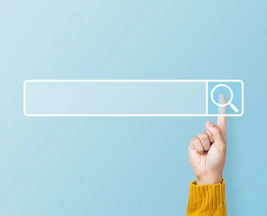 Hand pointing at a digital search bar icon on a blue background, symbolizing online search or internet browsing.
