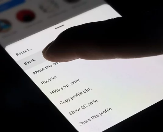 A person clicking 'block' on their social media.