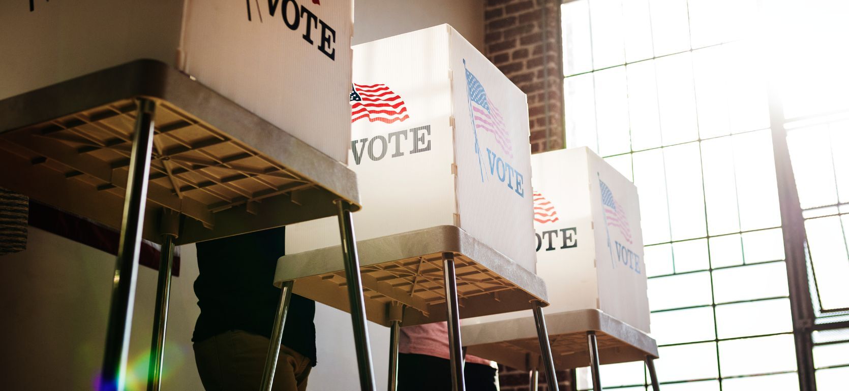 Three voting booths with sunlight coming in through the window.