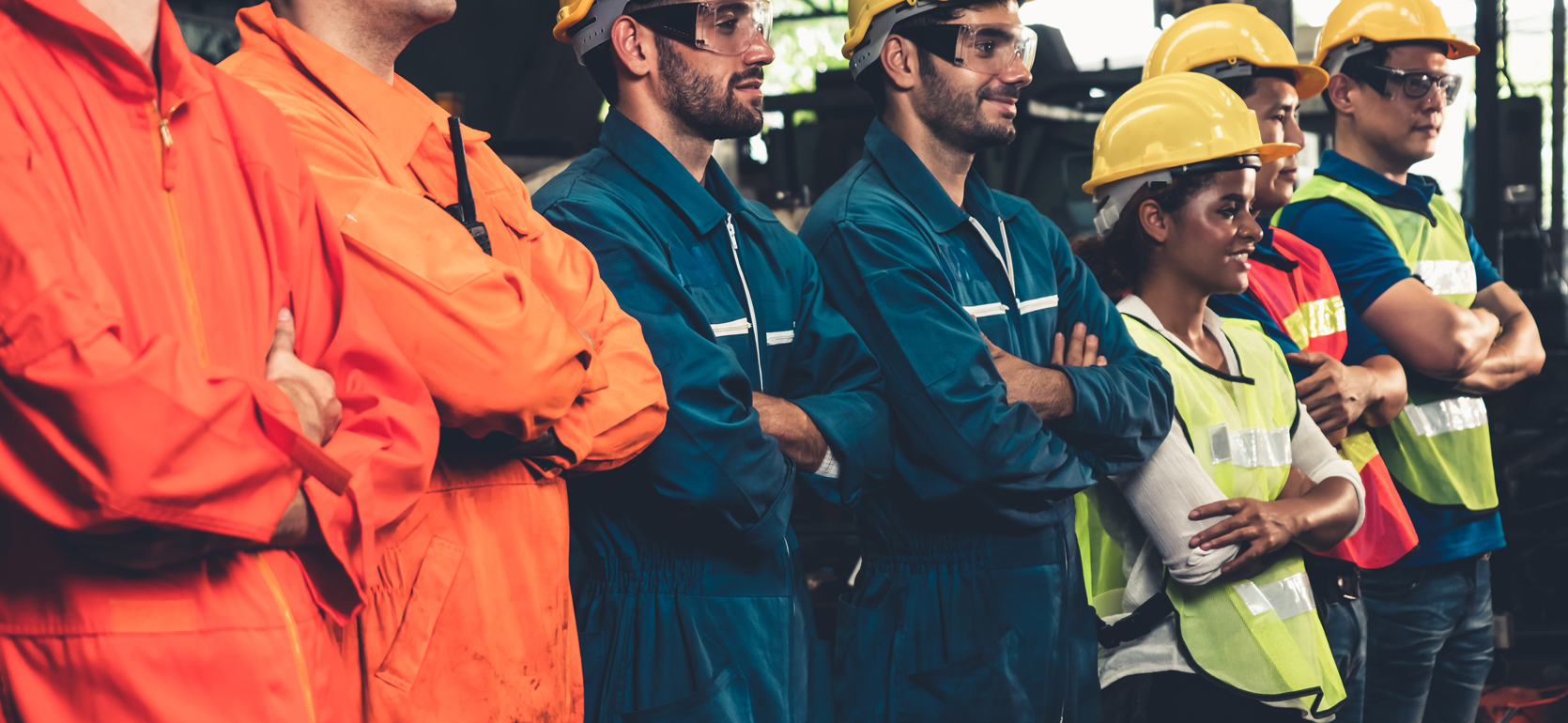 Factory workers standing in line wearing uniforms and hardhats