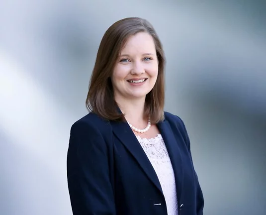 Photo of Allison Collins wearing a white blouse and a blue dress jacket.