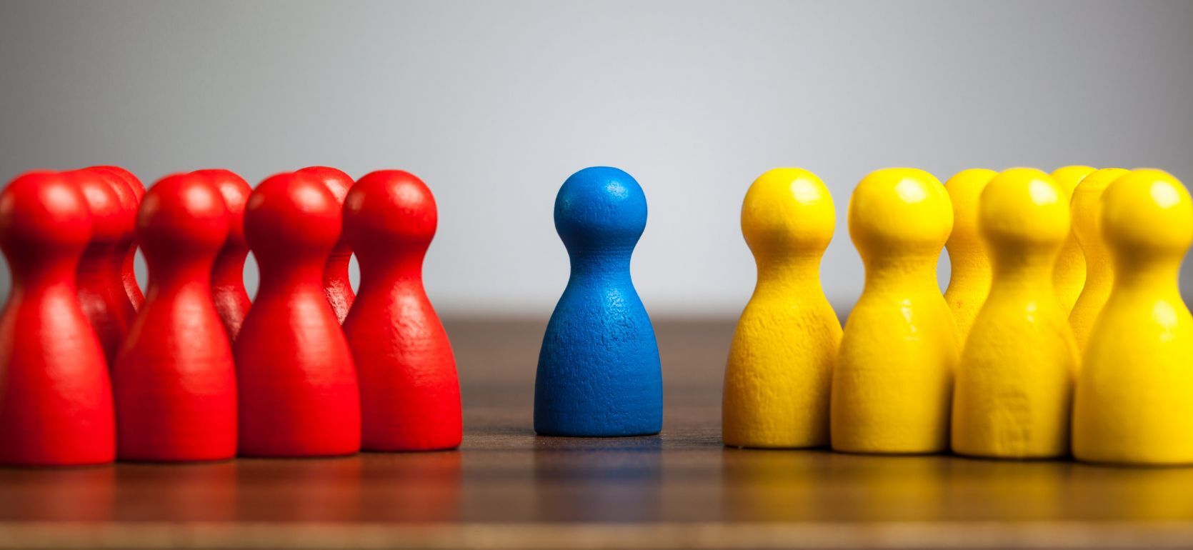 A photo of a group of red game pieces on the left, a single blue piece in the middle, and a group of yellow on the right.