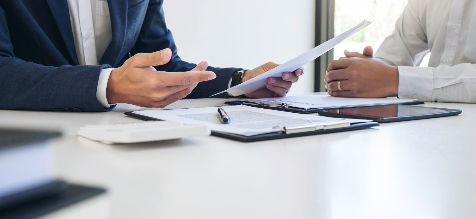 Two people talking over papers on a desk.