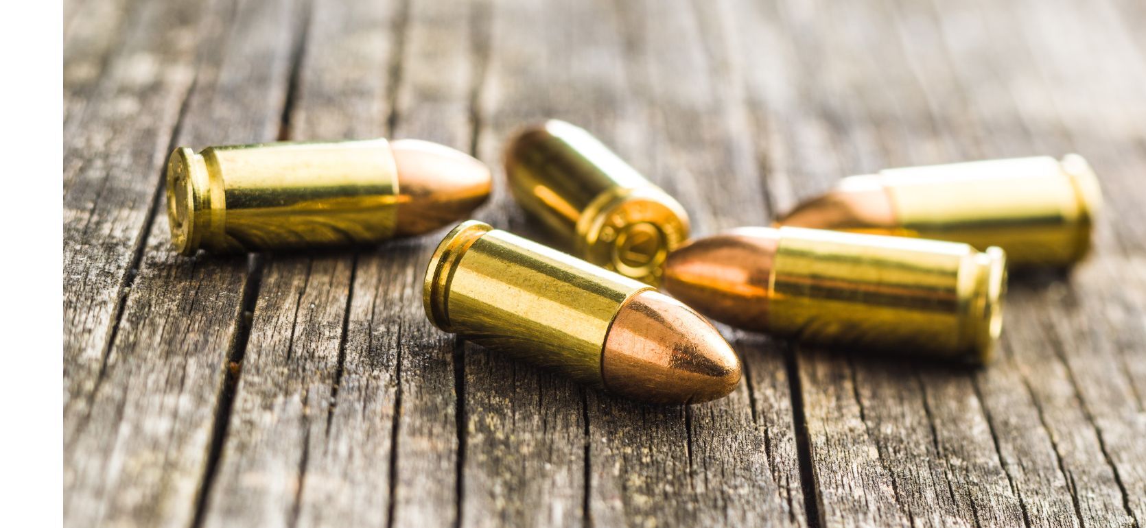 A pile of gun bullets on a wood table.