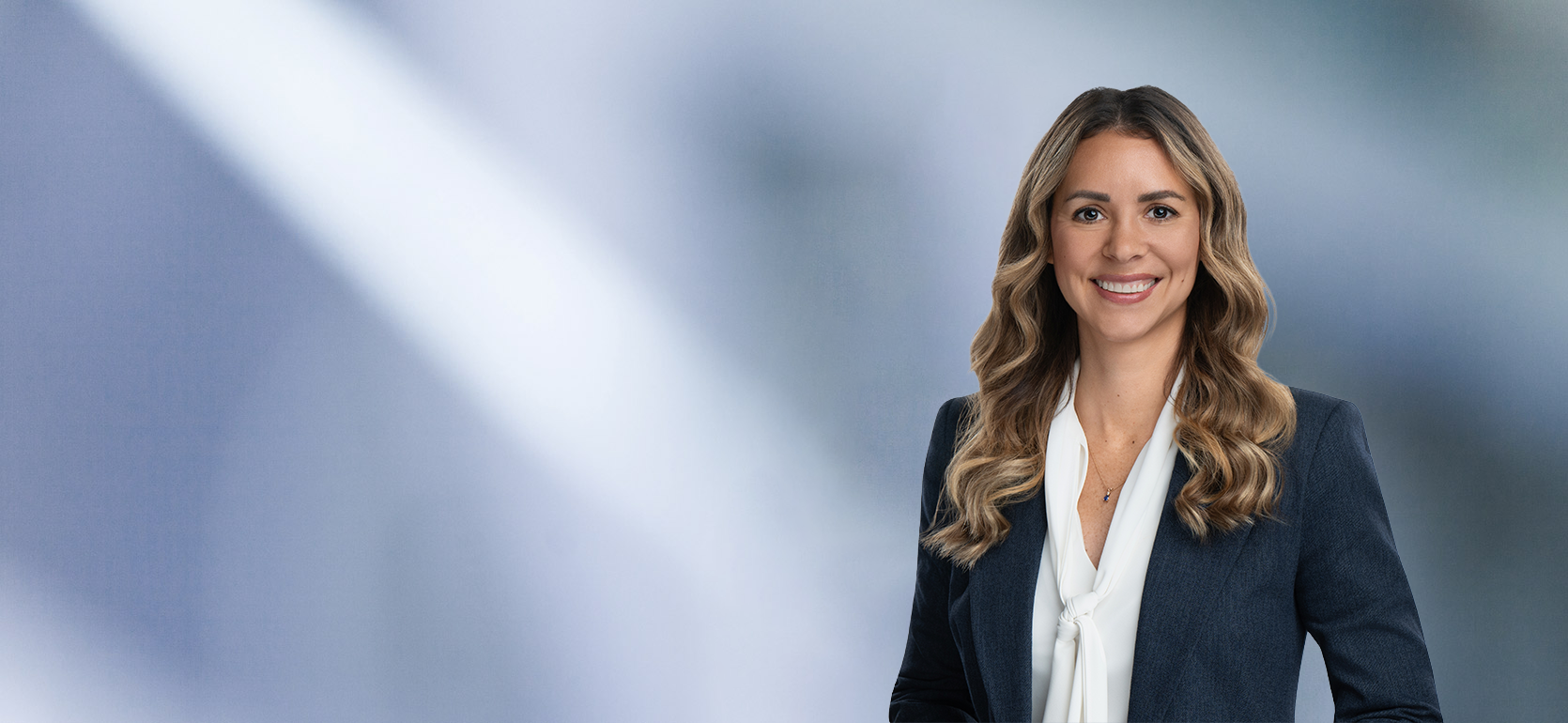 Blonde attorney, Lisa Gallagher, smiles at camera, wearing white blouse and blue sport coat.
