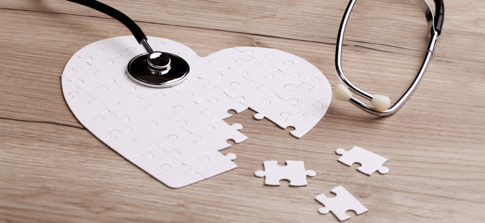 Heart shaped jigsaw puzzle with pieces missing with a stethoscope on top
