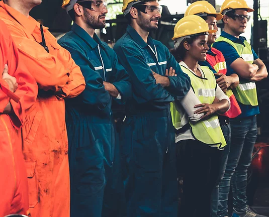 Factory workers standing in line wearing uniforms and hardhats