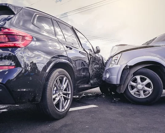 Two SUVs involved in a serious collision on a road, with one vehicle crashing into the side of the other. Visible damage includes a crushed side door and a crumpled front bumper.