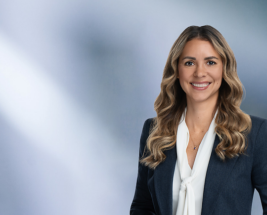 Blonde attorney, Lisa Gallagher, smiles at camera, wearing white blouse and blue sport coat.