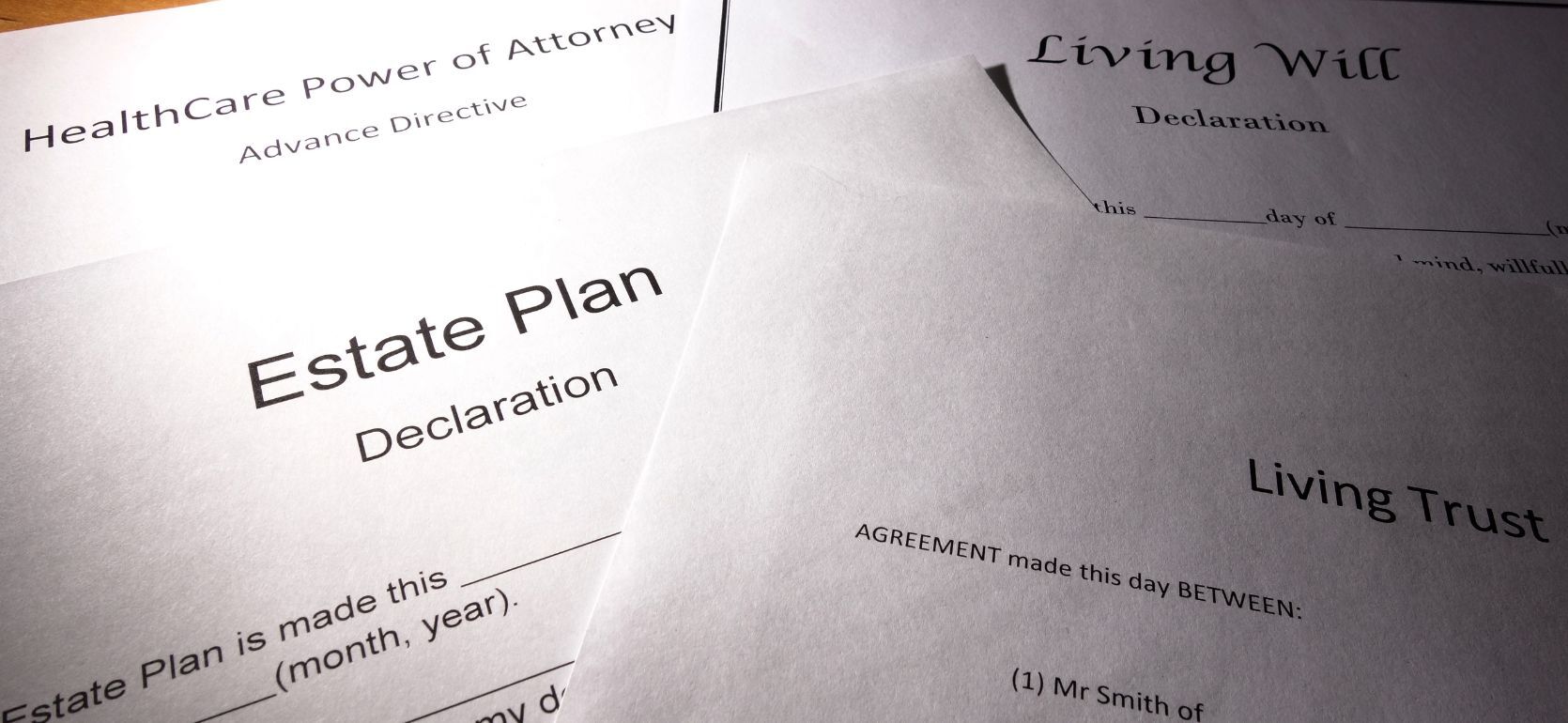 Living Will, Healthcare Power of Attorney, Estate Plan, and Living Trust documents on a table with a binder clip at the top.