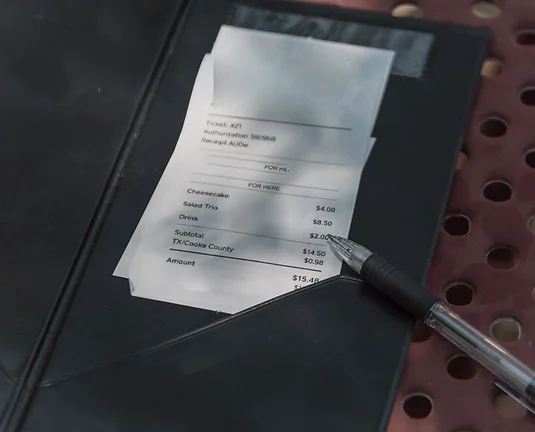 Close-up open leather bill holder with restaurant check and pen