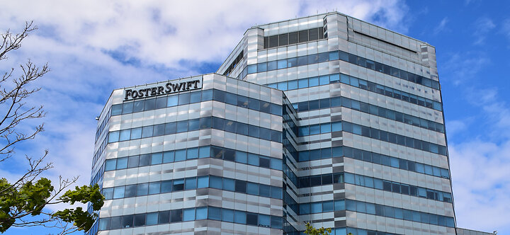 Modern glass high-rise office building in Southfield, Michigan with reflective windows and a blue sky in the background. The “Foster Swift” logo is prominently displayed near the top corner of the building.
