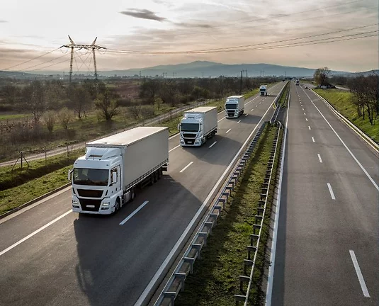 4 semi-trucks driving on the road.