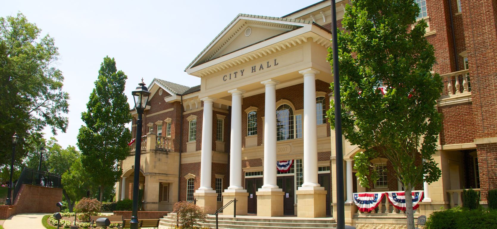 Picture of a city hall surrounded by trees and a blue sky.