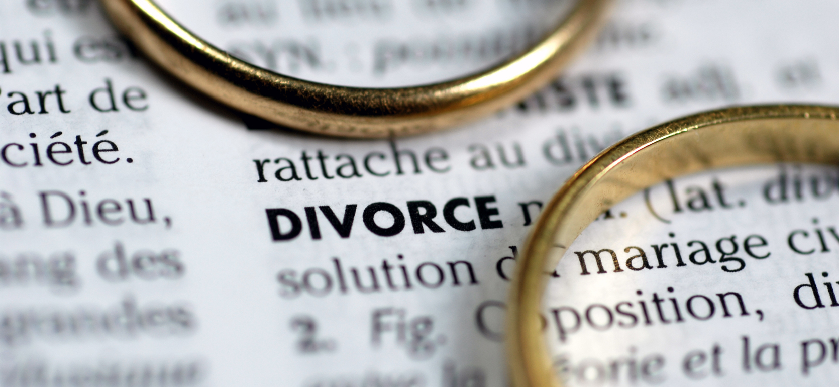 Dictionary definition of divorce with two gold rings around the printed paper