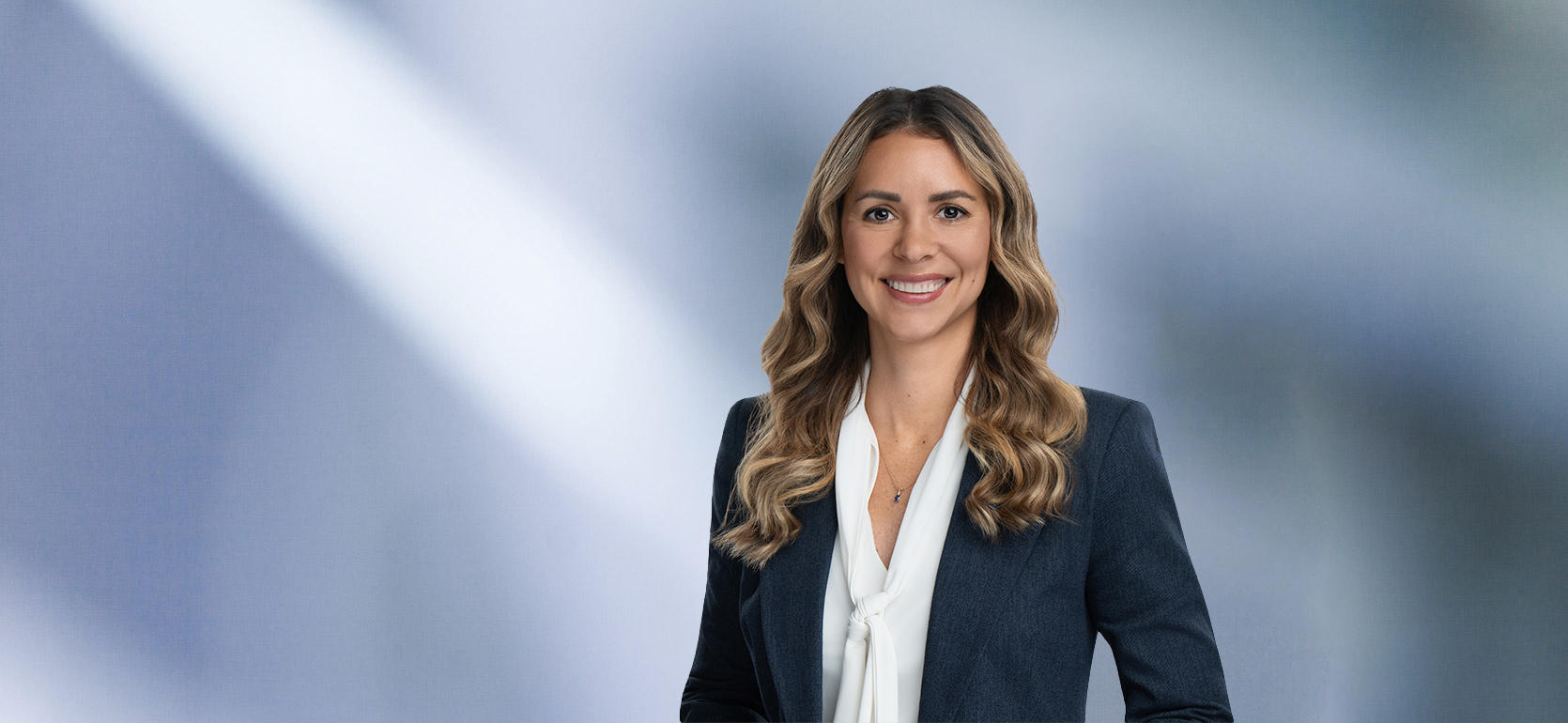 Blonde attorney, Lisa Gallagher, smiles at camera, wearing white blouse and blue sport coat.