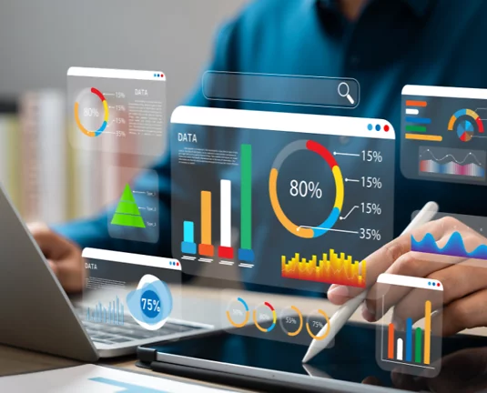 Person interacting with digital analytics dashboard on tablet and laptop, displaying various data visualizations including bar graphs, pie charts, and line graphs.