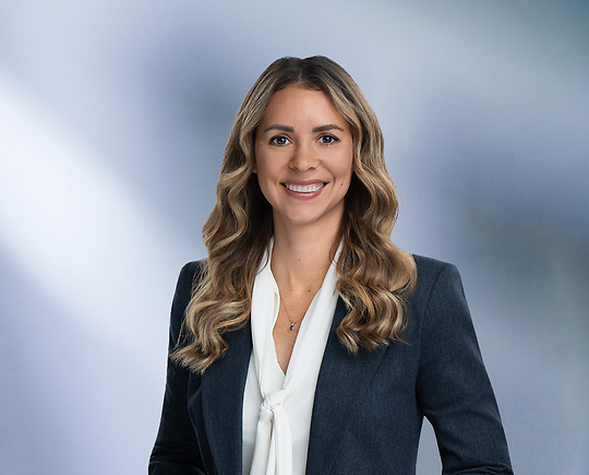 Blonde attorney, Lisa Gallagher, smiles at camera, wearing white blouse and blue sport coat.