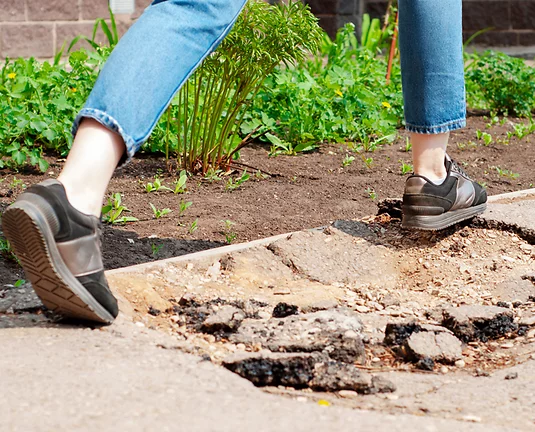 Pair of legs on sidewalk sidestep a pothole in the concrete