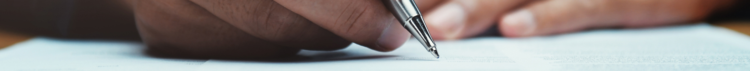 A hand writes on paper with pen