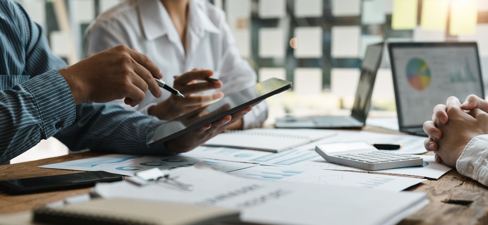 Three people sitting at a table of business papers and a laptop.