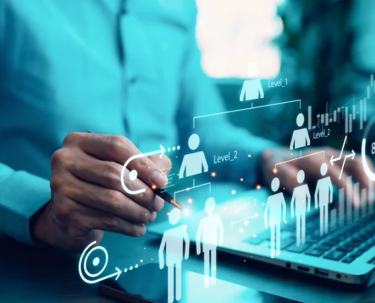 Business professional using a laptop with a digital interface displaying icons of people and network connections, representing human resources or digital networking.
