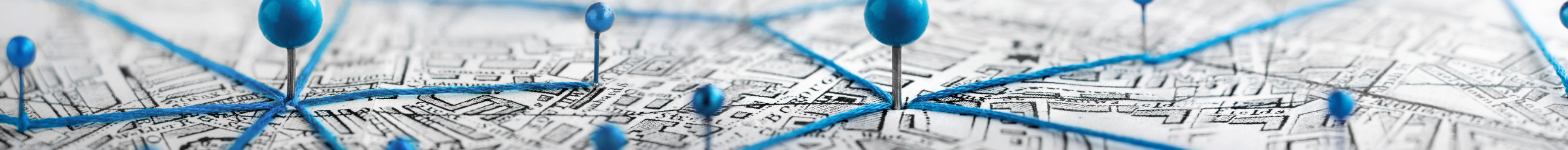 Close-up of a city map with blue push pins connected by blue string, indicating networked locations or points of interest