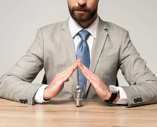 partial view of businessman showing protection gesture above light bulb isolated on grey
