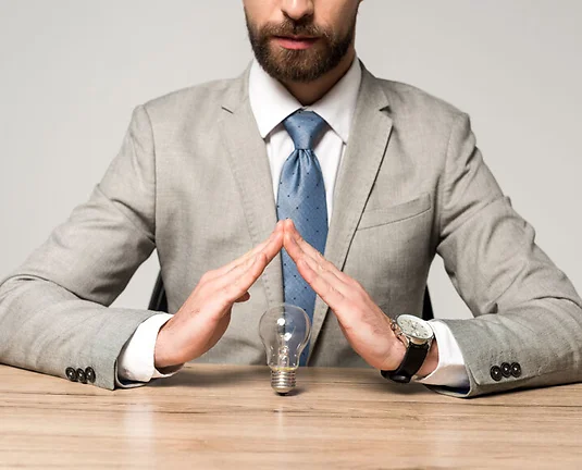partial view of businessman showing protection gesture above light bulb isolated on grey