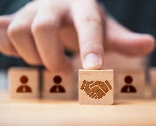 Hand putting hand shaking which print screen on wooden cube block in front of human icon for business deal and agreement concept