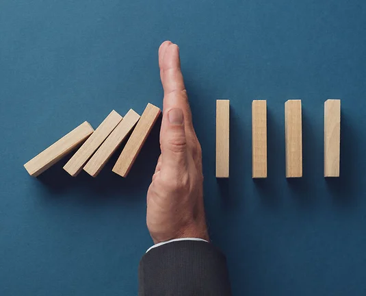 Business crisis manager stopping falling dominos from collapsing