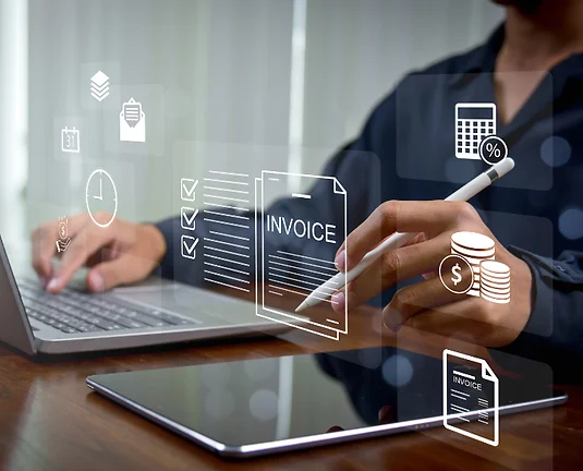 Someone sitting at a laptop with various white invoice and money graphics floating across the image.